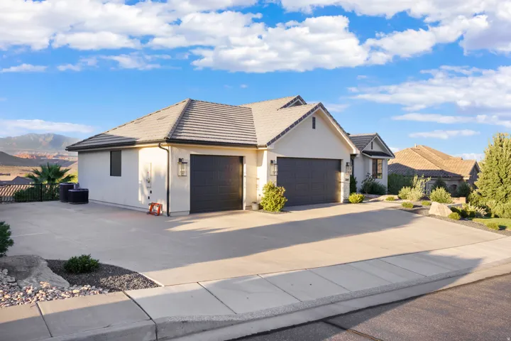 Stucco exterior residence featuring a multi-car garage, concrete driveway, and a tiled roof
