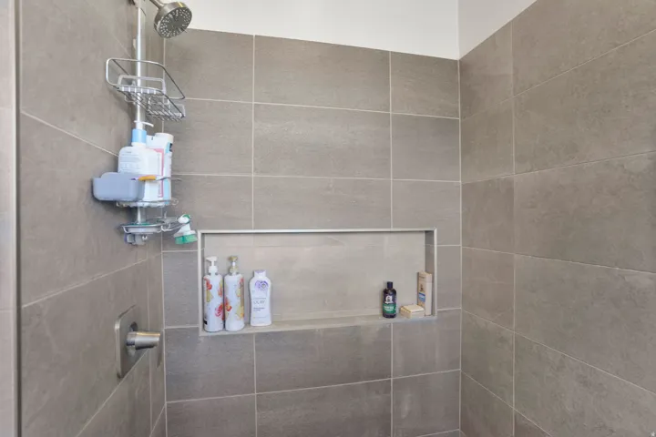 Primary bathroom - shower with a built-in recessed niche and gray tile surround