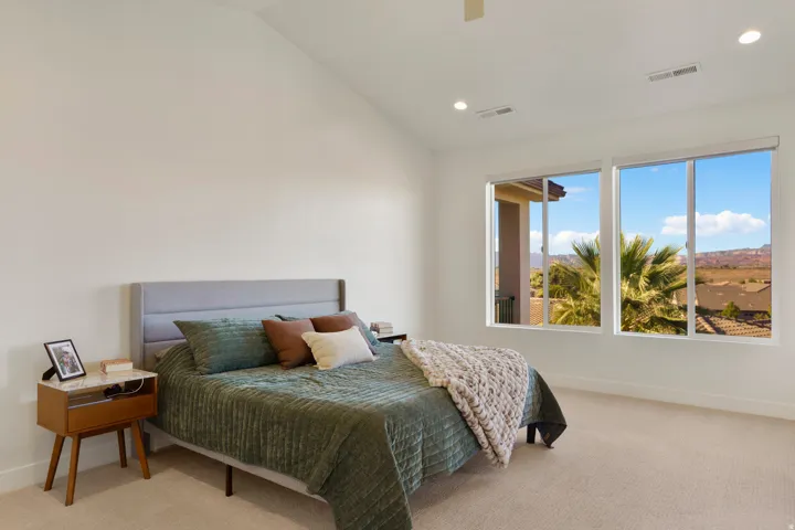 Primary bedroom with vaulted ceiling and recessed lighting