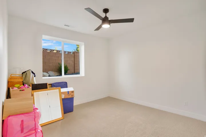 Carpeted room with a ceiling fan, a window, and white walls