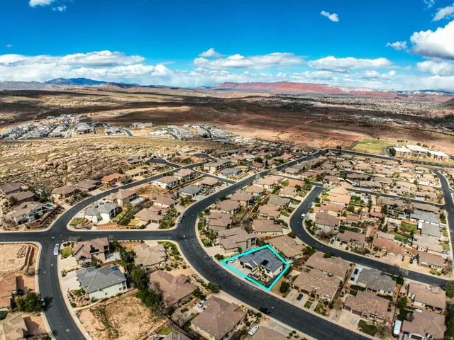 Aerial perspective showcasing a residential neighborhood with arid landscaping and distant mountains under a blue sky with scattered clouds