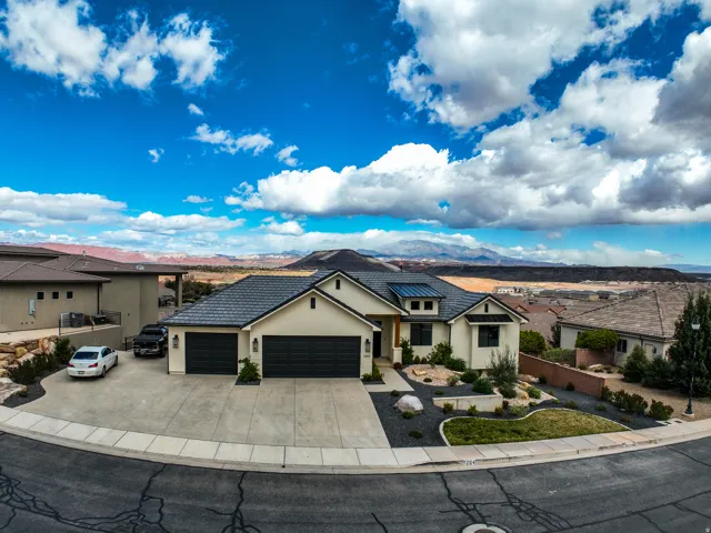 Aerial view - stucco exterior with a tiled roof, a three-car garage, and a concrete driveway