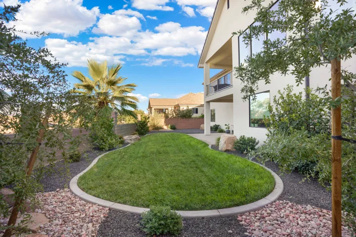 Expansive backyard featuring a manicured lawn, established landscaping, and a multi-level exterior with a covered balcony