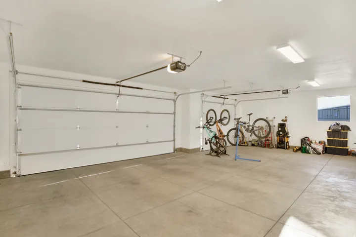 Integrated two-car garage featuring automatic overhead doors, concrete flooring, and ceiling-mounted fluorescent lighting