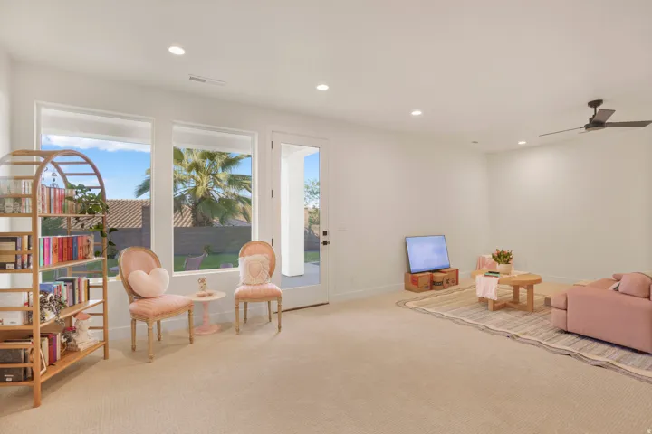 Recessed lighting and a ceiling fan illuminate a spacious room featuring wall-to-wall carpeting
