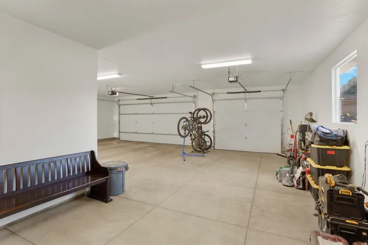 Spacious garage featuring two overhead doors, concrete flooring, and fluorescent lighting