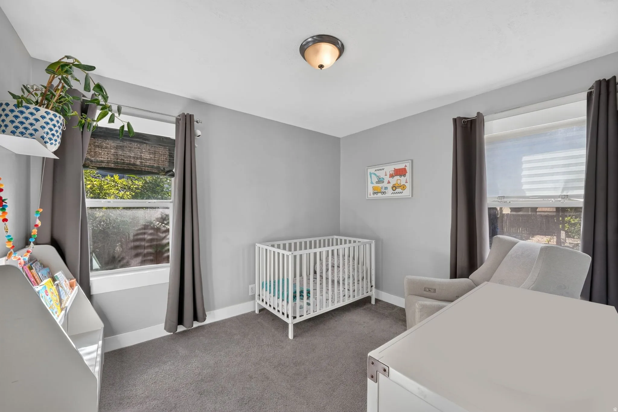 Neutral wall colors, carpeted flooring, two windows, and a ceiling-mounted light fixture