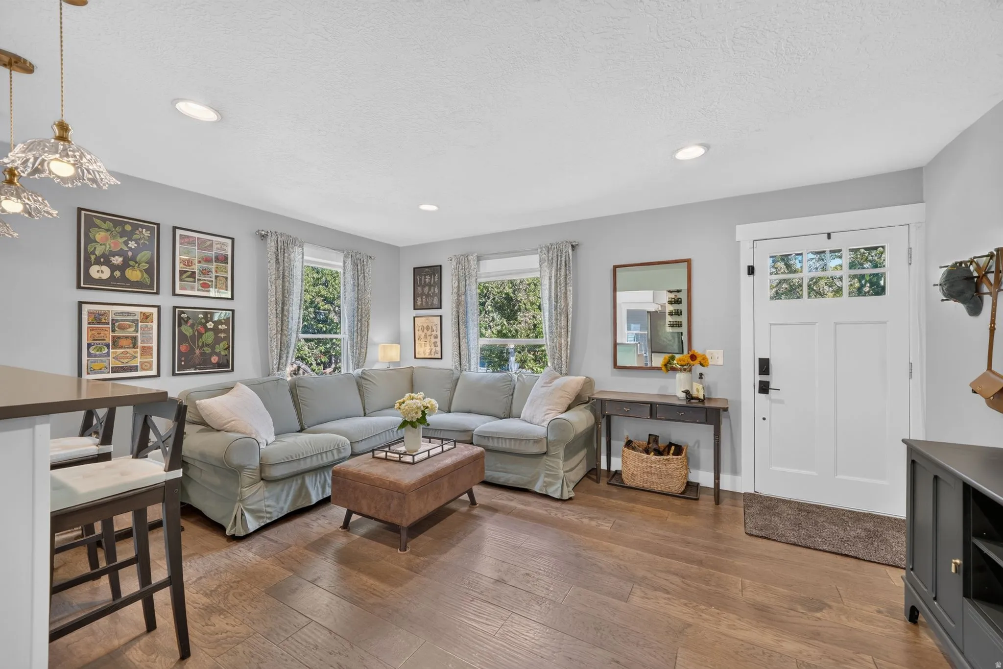 Recessed ceiling lighting, wood-finish flooring, white paneled front door with clear glass inserts, and a built-in breakfast bar