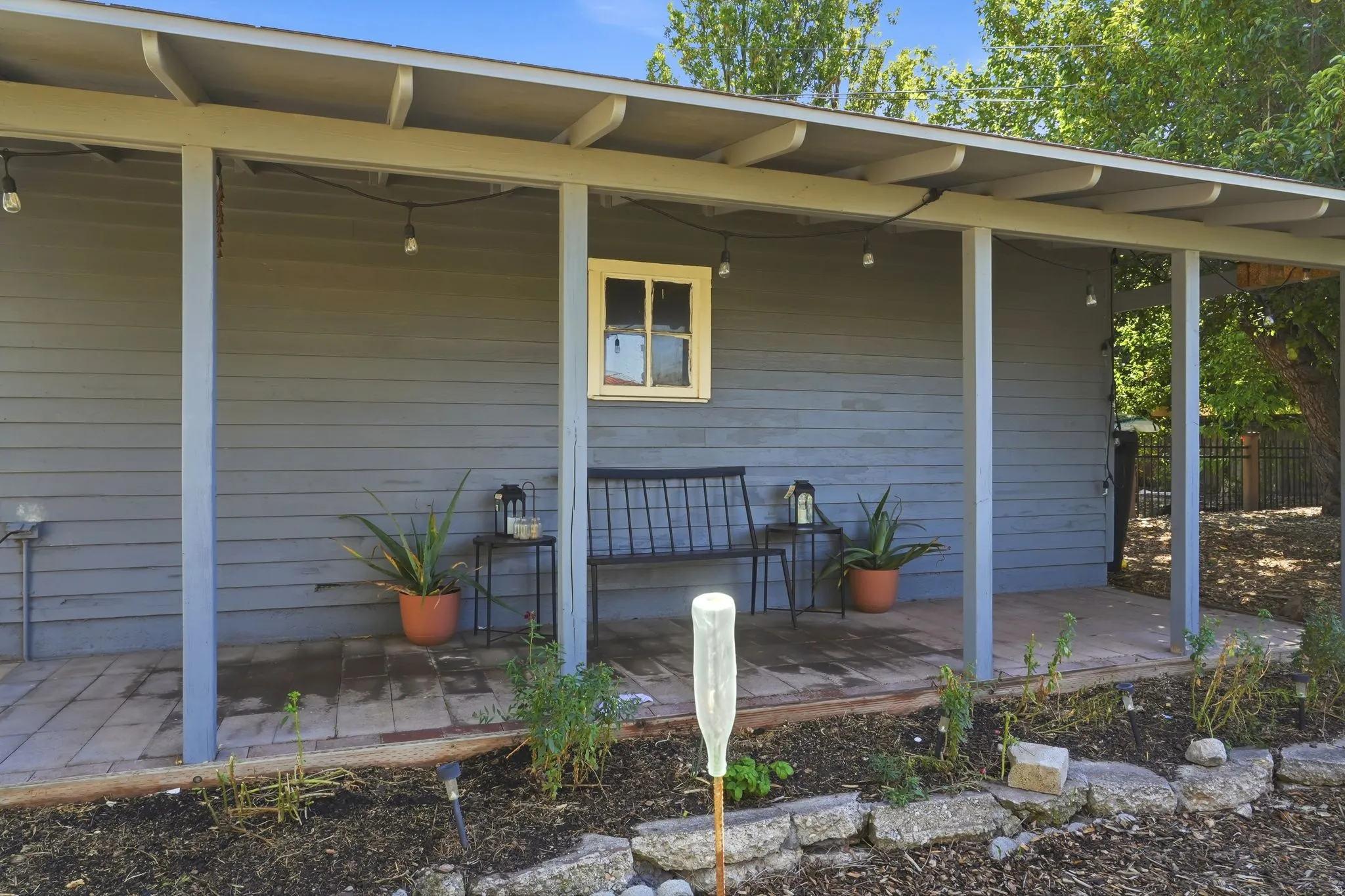 Covered porch with wood-finish flooring, plank siding, and a single window with trim