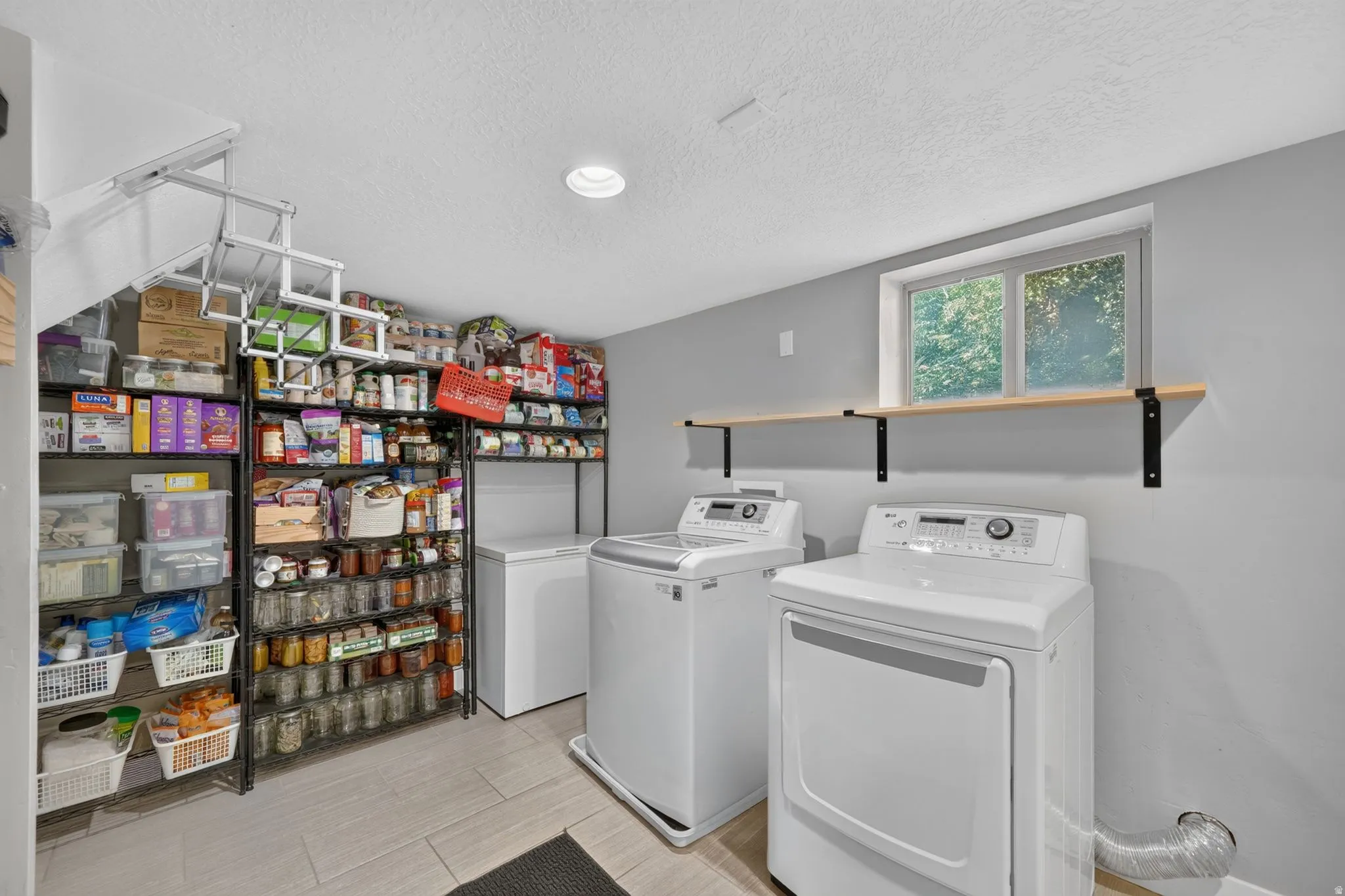 Utility space featuring tile flooring, built-in shelving, and a mounted shelf under a window
