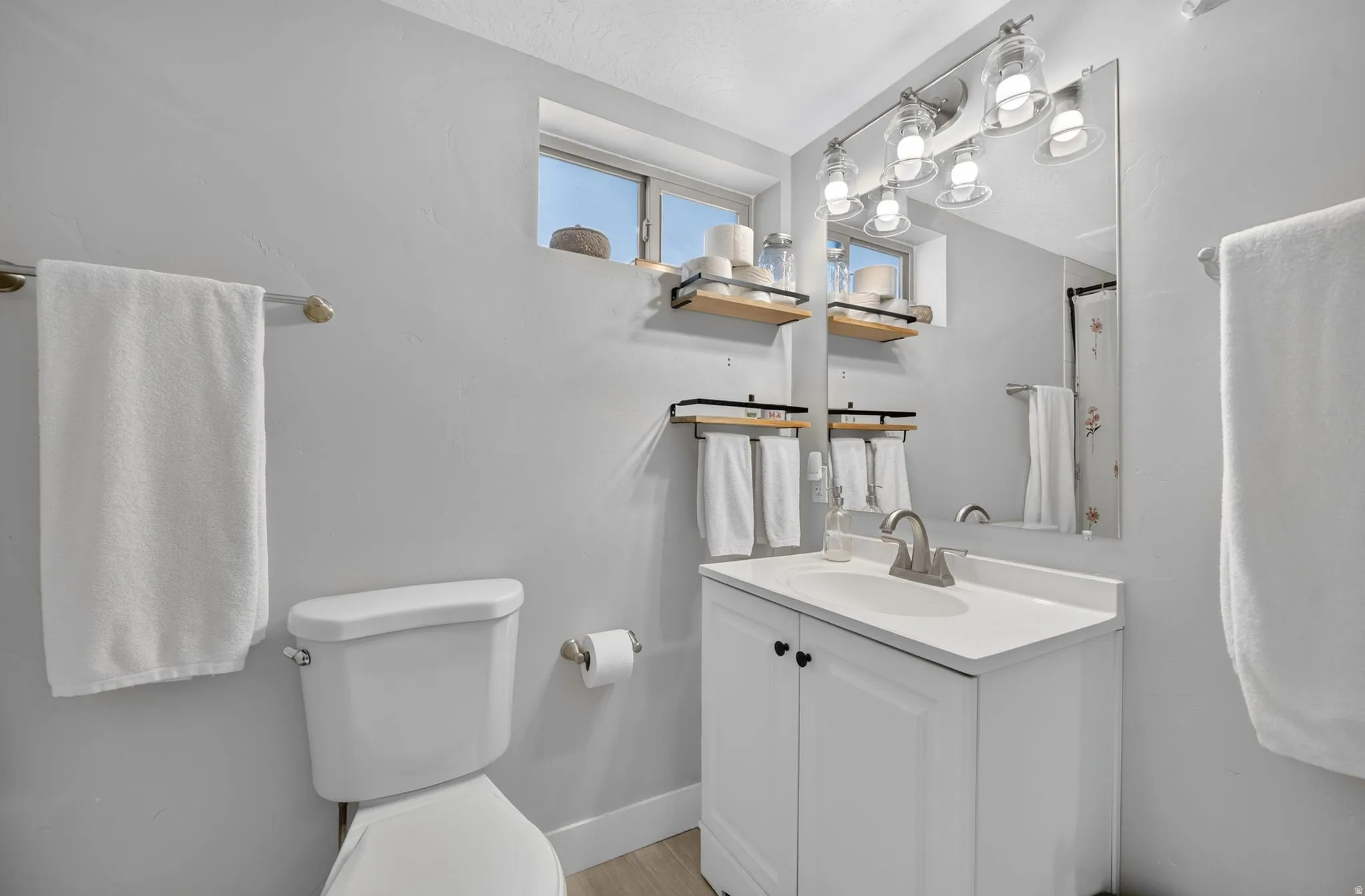 Vanity with white cabinetry, wall-mounted mirror, and overhead lighting