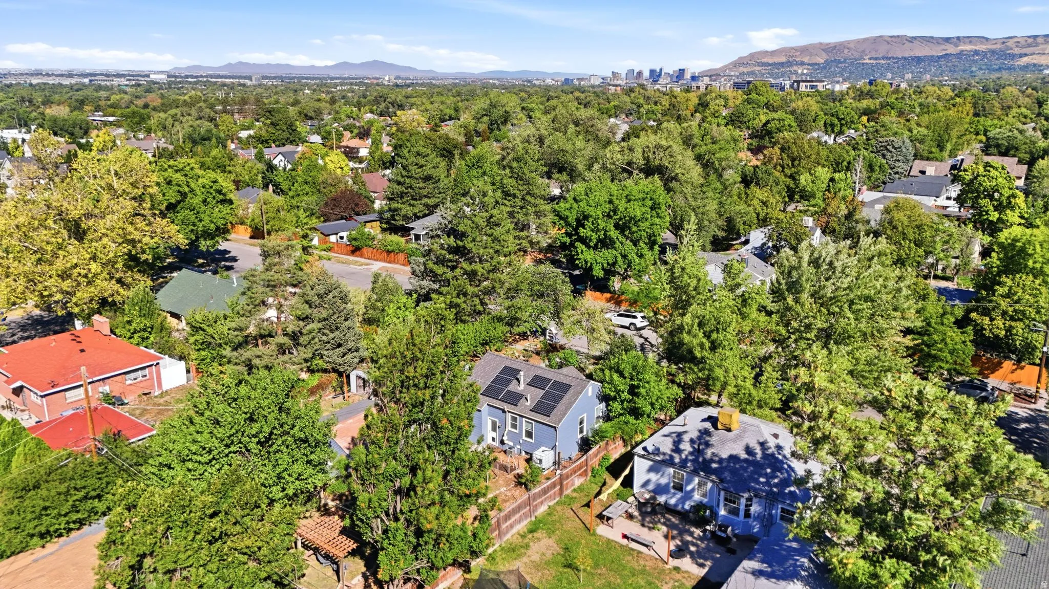 Suburban setting with mature trees and visible solar panels on a residential rooftop