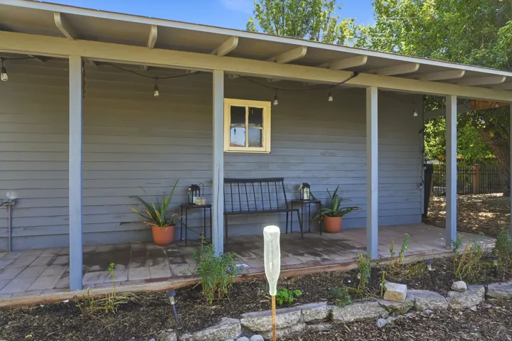 Covered porch with wood-finish flooring, plank siding, and a single window with trim