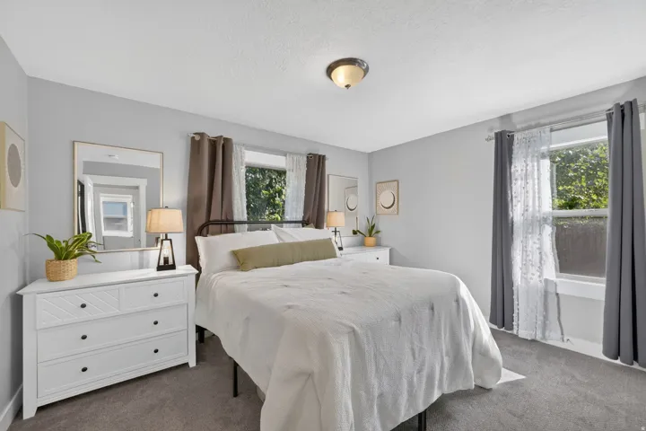 Carpeted room featuring light gray walls, two windows, and a flush-mount ceiling light fixture