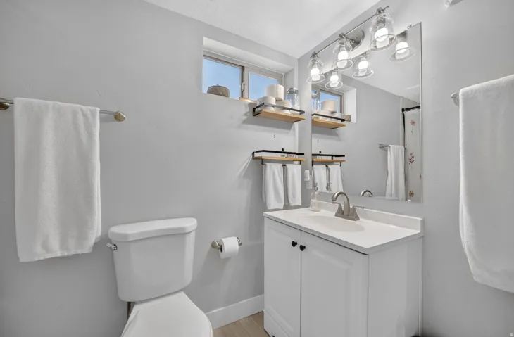 Vanity with white cabinetry, wall-mounted mirror, and overhead lighting