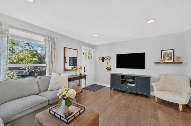 Hardwood flooring throughout, recessed lighting, and a white paneled entry door with glass inserts