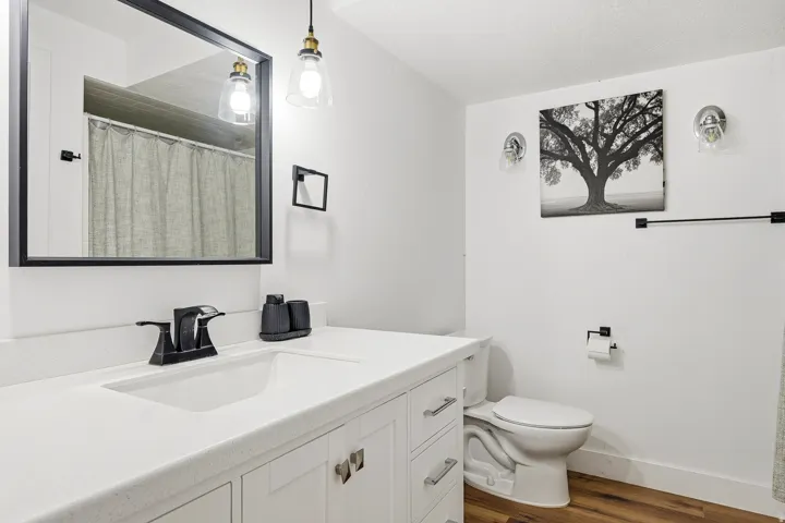 White vanity with shaker-style cabinetry, a built-in rectangular sink, and a white countertop
