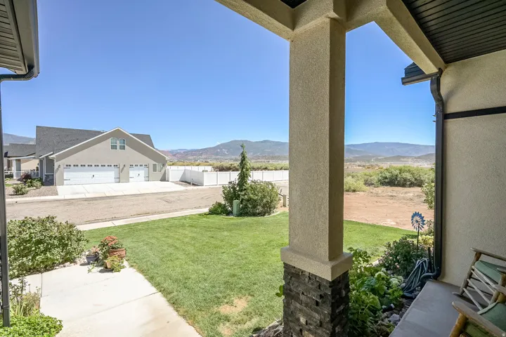 Front porch with stone-clad columns, covered patio, and a manicured lawn