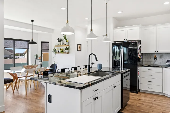 Kitchen featuring an island with a sink, white cabinetry, integrated black appliances, a tile backsplash, and wood-finish flooring