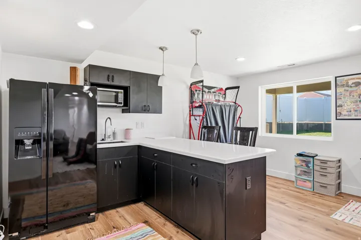 Kitchenette featuring wood-finish flooring, white countertops, dark cabinetry, and recessed lighting