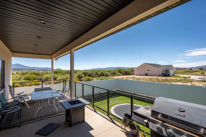Covered patio with recessed lighting, cable railing, and mountain backdrop