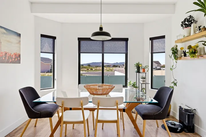 Wood-finish flooring, multiple windows with black trim, and a contemporary pendant light fixture