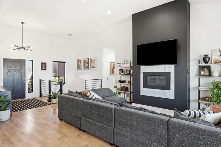 Vaulted ceilings, wood-finish flooring, and a contemporary fireplace with a tiled surround