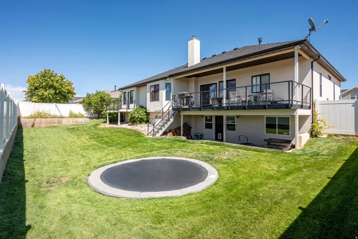 Expansive backyard with a manicured lawn, multi-level deck featuring black metal railings, and a walk-out lower level