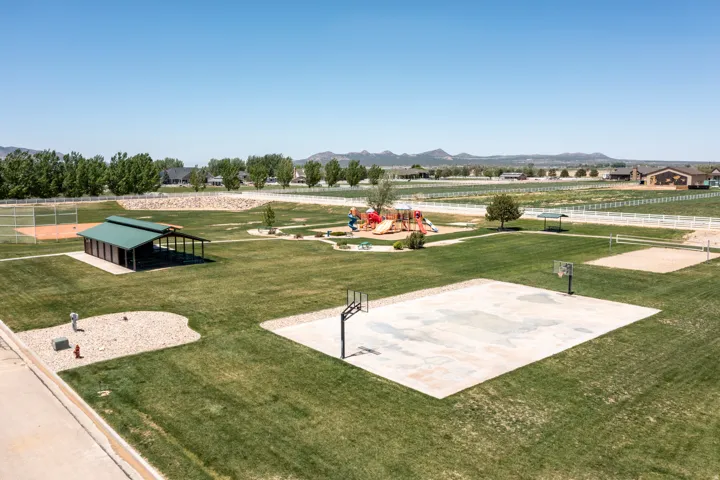 Expansive community green space featuring a covered pavilion, basketball court, sand volleyball court, and a playground