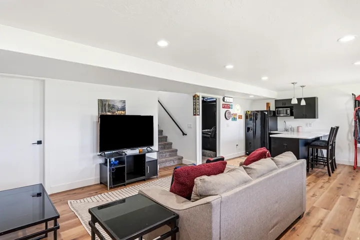 Open-concept living area featuring wood-finish flooring, recessed lighting, and a built-in wet bar with pendant lighting