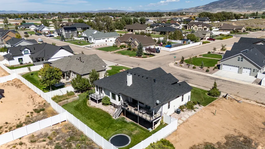 White exterior with a dark-shingle roof, featuring a multi-level deck and a fenced backyard