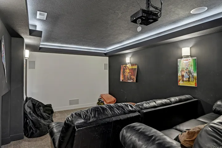 Integrated ceiling projector, recessed ceiling speakers, wall-mounted sconces, ceiling strip lighting, and a neutral-toned projection wall
