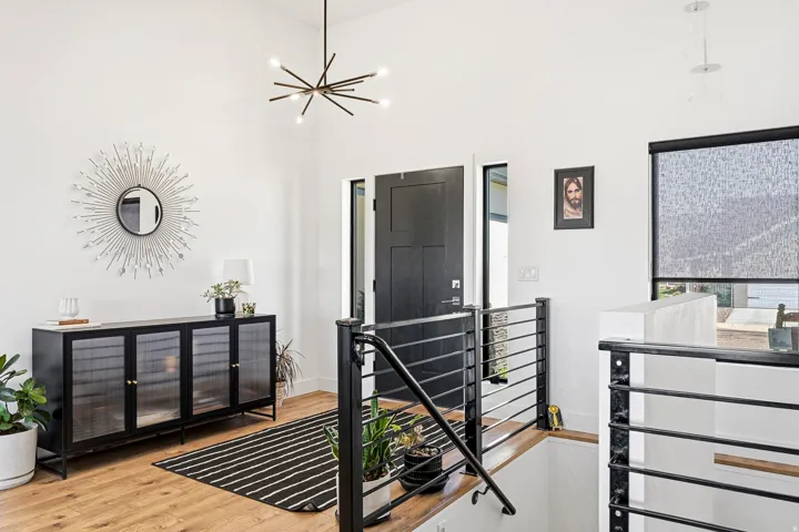 Bright entryway with light wood-finish flooring, a modern chandelier, and dark-paneled door