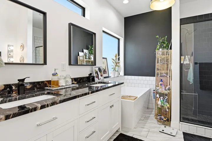 Dual vanity with dark stone countertops, undermount sinks, and matte black fixtures