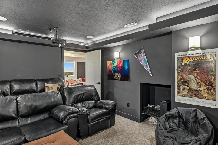 Recessed lighting, ceiling-mounted projector, wall sconces, integrated built-in shelving, and neutral carpeting