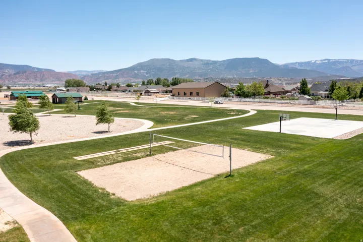 Expansive green space featuring a sand volleyball court, basketball court, and paved walking paths