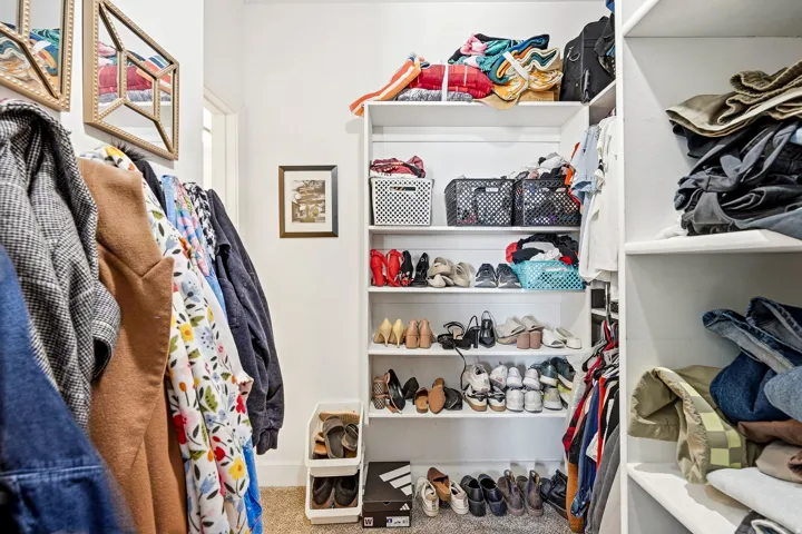 Built-in white shelving, permanent clothing rods, and a neutral carpeted floor