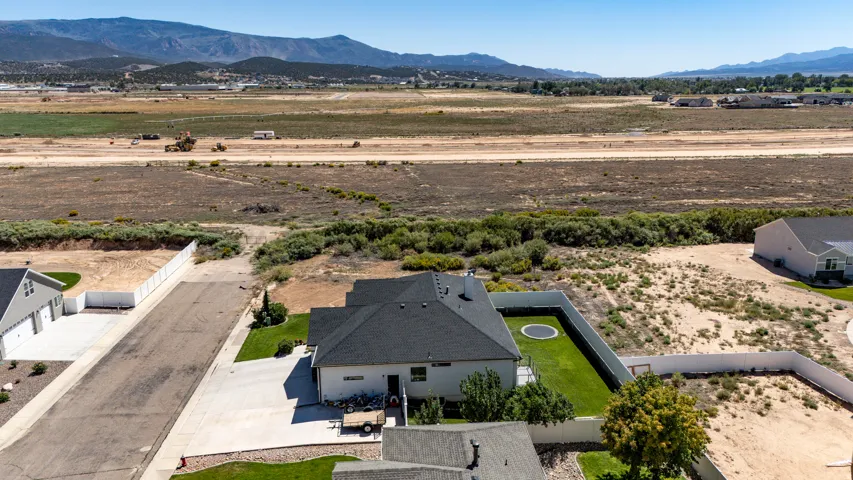 Expansive mountain backdrop with a substantial lot, featuring a manicured lawn and a privacy fence