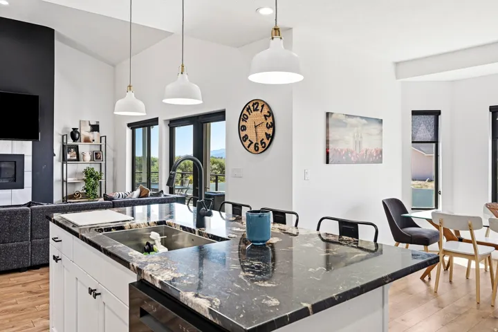 Kitchen island with dark stone countertops and an undermount sink