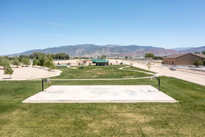 Landscaped green space featuring a basketball court, walking paths, and a community building