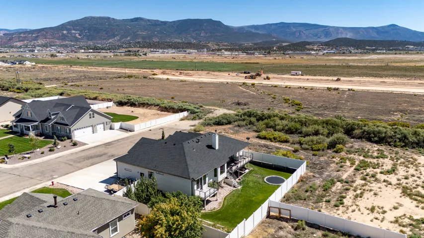 Single-family residence with a black shingle roof, deck, and green lawn