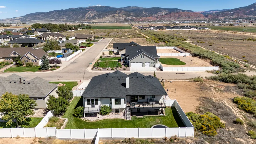 Multi-level residence with a rear deck and lower patio, featuring a fenced backyard with a manicured lawn