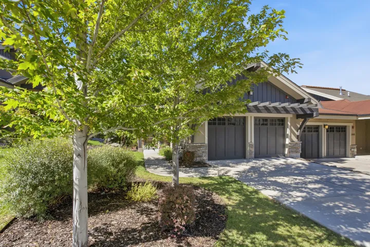 Attached multi-car garage with carriage-style doors, stone accents, and an overhead pergola