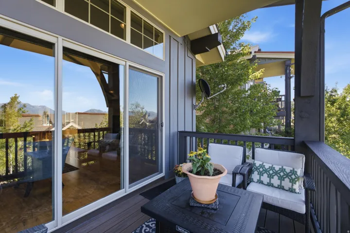 Outdoor balcony with dark composite decking, a dark railing, and sliding glass doors