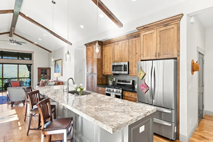 Kitchen featuring a large island with an undermount sink, pendant lighting, stainless steel appliances, and wood cabinetry