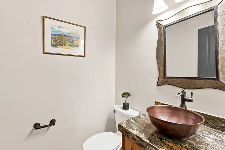 Vanity with a copper vessel sink, dark-toned faucet, and a stone countertop