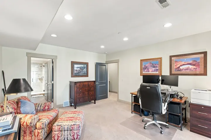Recessed ceiling lighting, light-toned wall paint, neutral carpeting, and a glass-enclosed shower