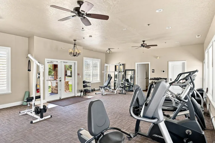 Fitness center featuring multiple exercise machines, ceiling fans, recessed lighting, and plantation shutters