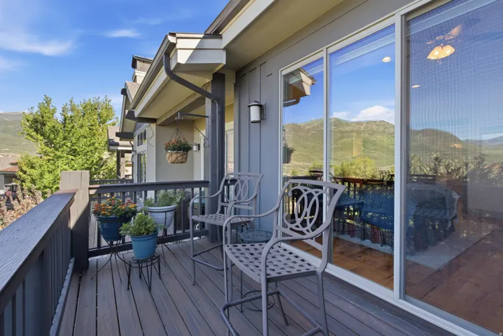 Expansive exterior deck with wood-finish flooring, dark-stained railing, and a sliding glass door