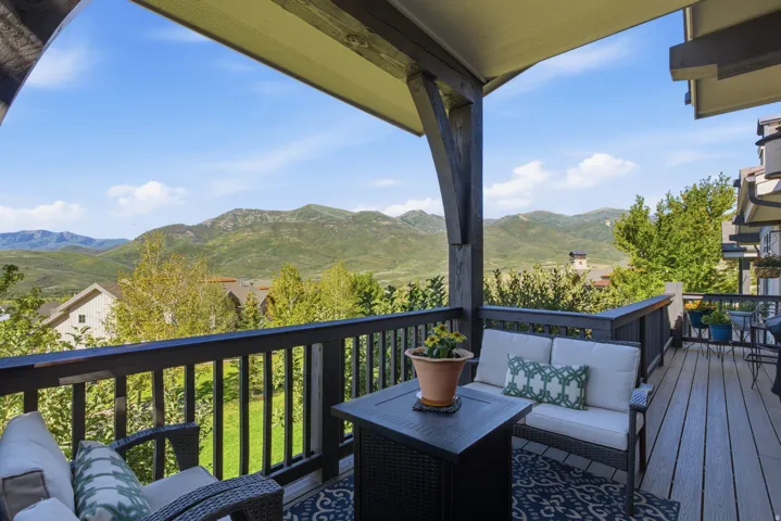 Expansive covered deck featuring composite decking, dark wood railings, and exposed beam ceiling supports
